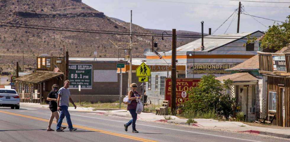 Visitors walk across the quiet main street, only one in a mask, in Goldfield on Tuesday, August ...