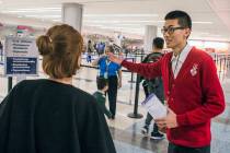 Shingling Guo, right, a Malarian-speaking ambassador, assists a passenger from Hainan Airline f ...