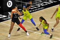 Las Vegas Aces' A'ja Wilson, left, looks to pass while under pressure from Dallas Wings' Astou ...