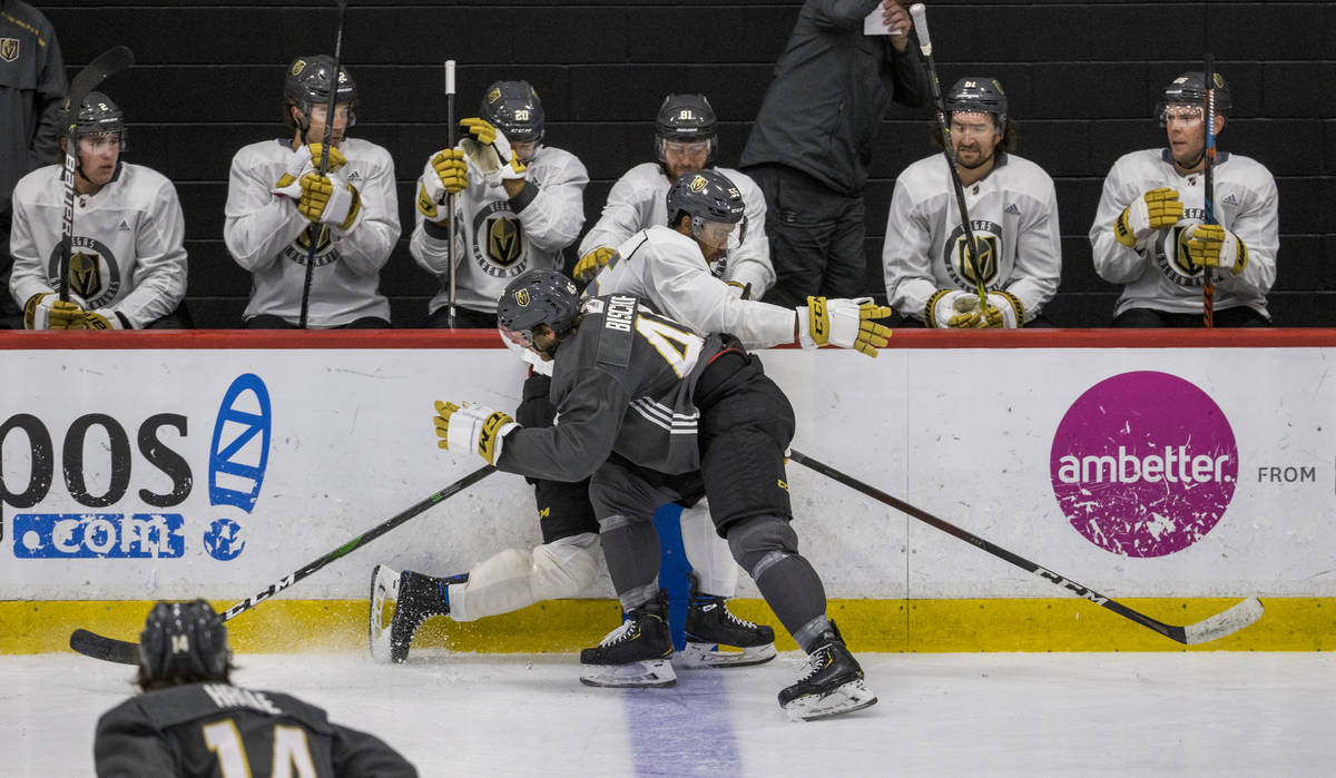 Vegas Golden Knights defenseman Jake Bischoff (45, left) puts a hard check on right wing Keegan ...