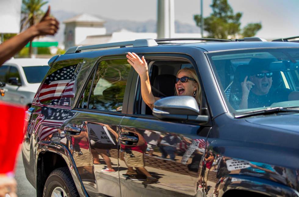 A driver and passenger show their support as they pass by a No Mask Nevada rally to oppose the ...