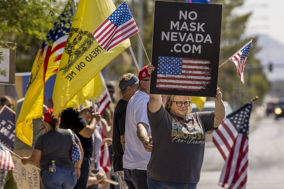 Supporters hold signs and flags during the No Mask Nevada rally to oppose the face mask mandate ...