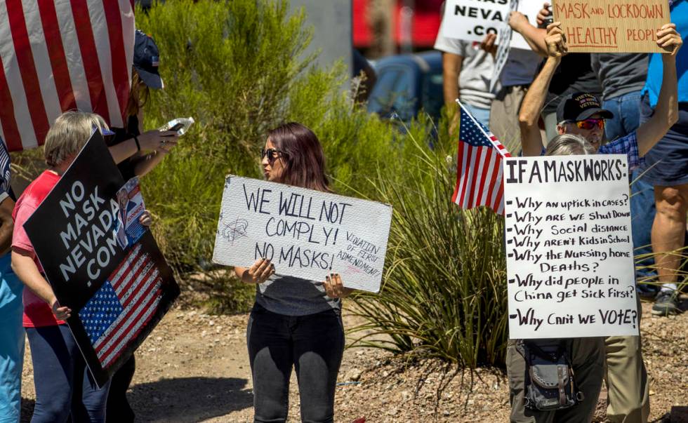 Supporters display a variety of signs during a No Mask Nevada rally to oppose the face mask man ...