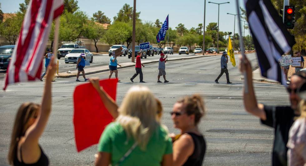 Supporters carrying flags and signs make another cross of traffic during the No Mask Nevada ral ...