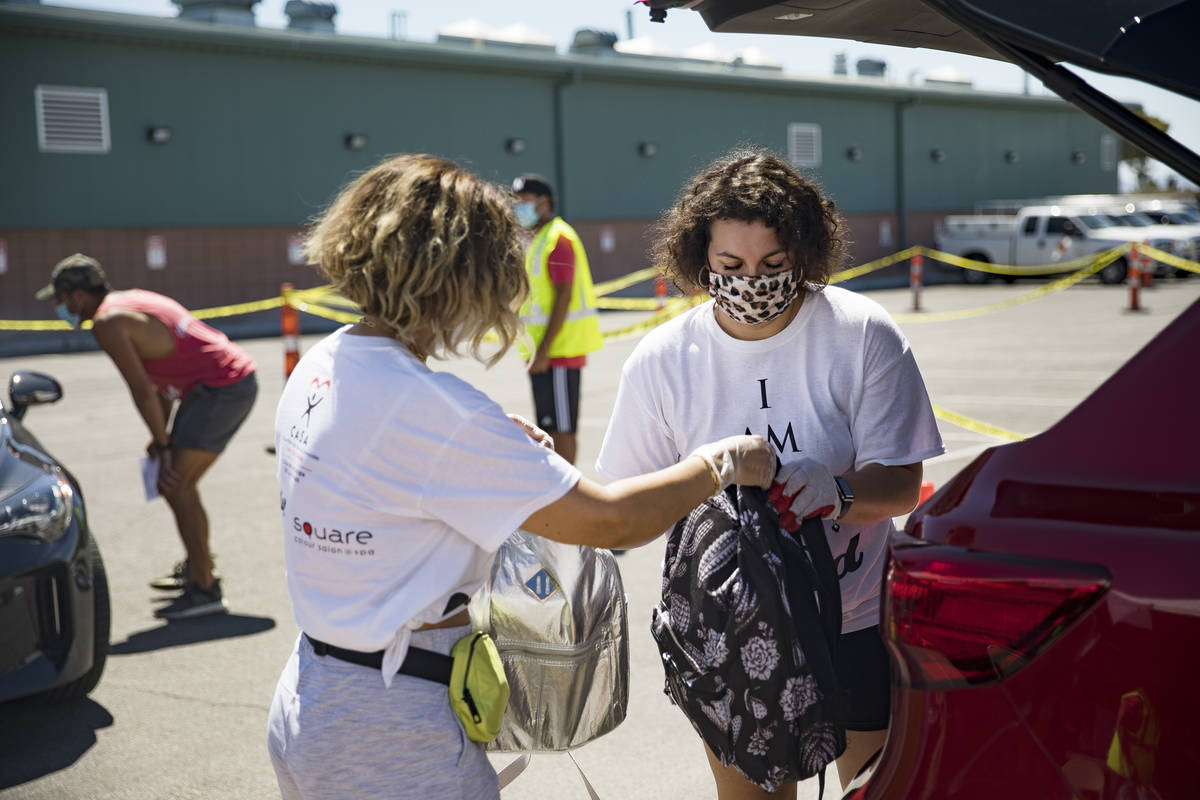 Volunteers Theresa Broussard, left, hands backpacks to Vicky Murillo, right, to put in a car of ...