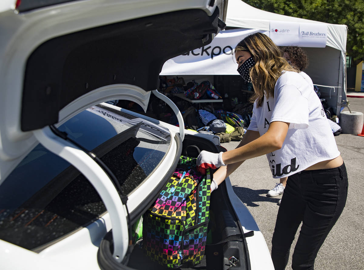 Volunteer Raquel Lavin places a backpack in the back of a car at a back-to-school drive made dr ...