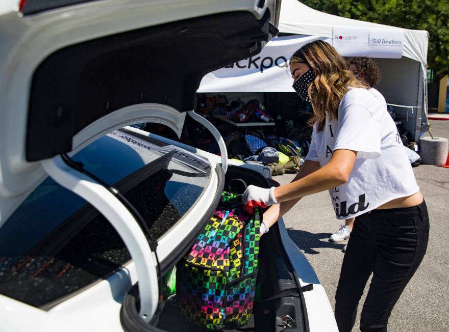 Volunteer Raquel Lavin places a backpack in the back of a car at a back-to-school drive made dr ...