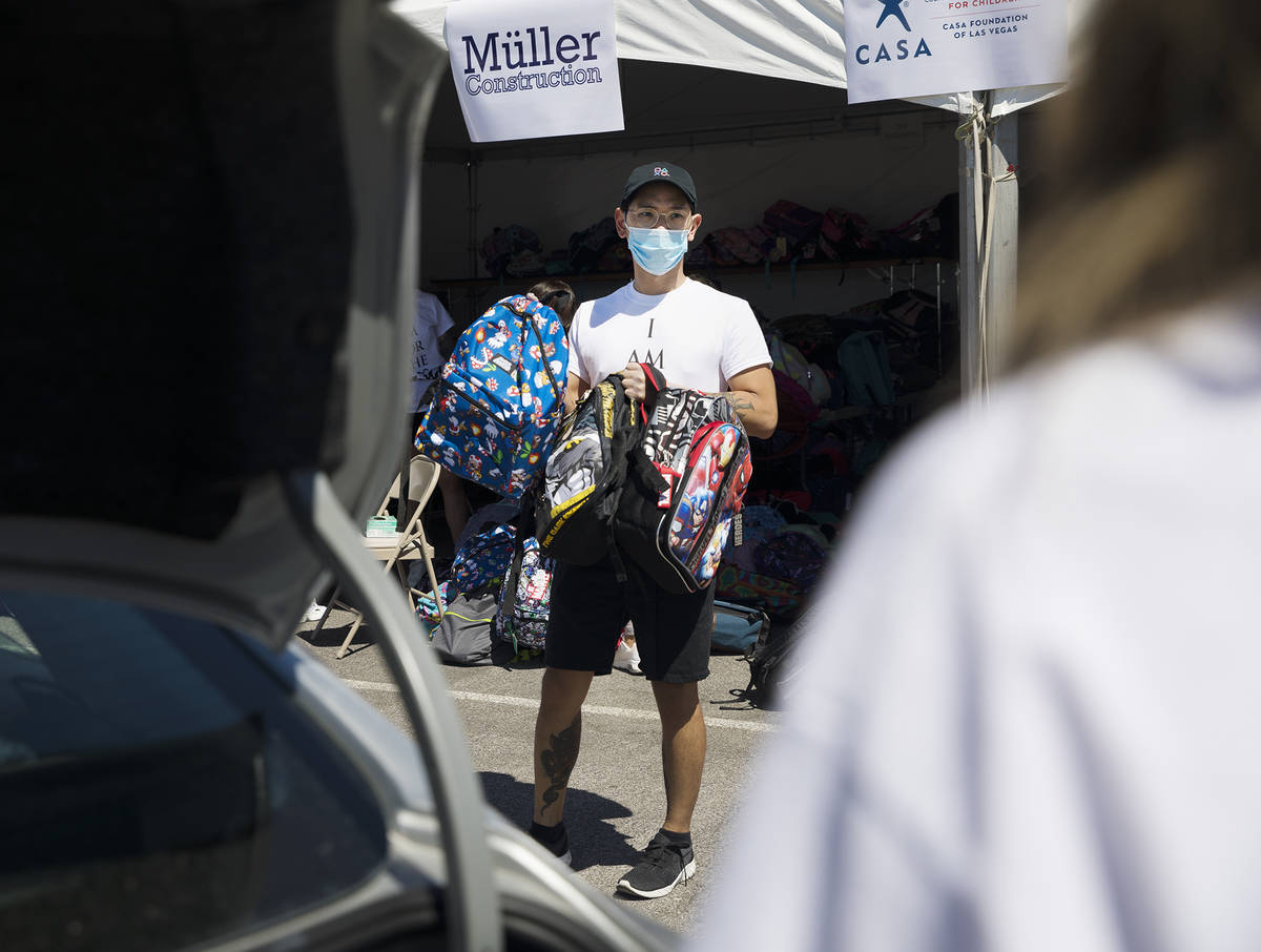 Volunteer Dillon Mones shows backpacks to foster children in a car at a back-to-school drive ma ...
