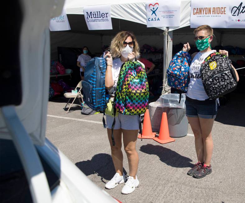 Volunteers Theresa Broussard, left, and Alexis Von Schlieder, right, show backpacks to foster k ...