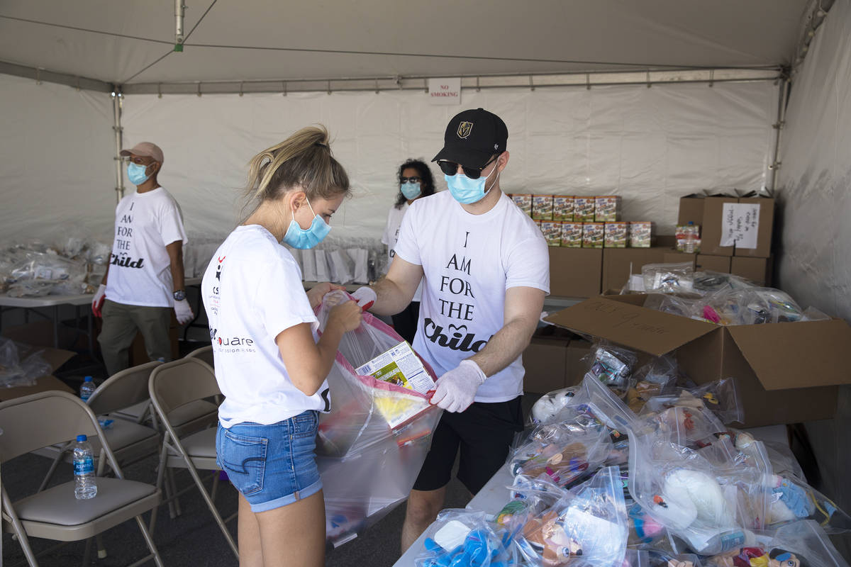 Volunteers Shally Matlovick, left, and Max Guy, right, gather supplies together to give away at ...