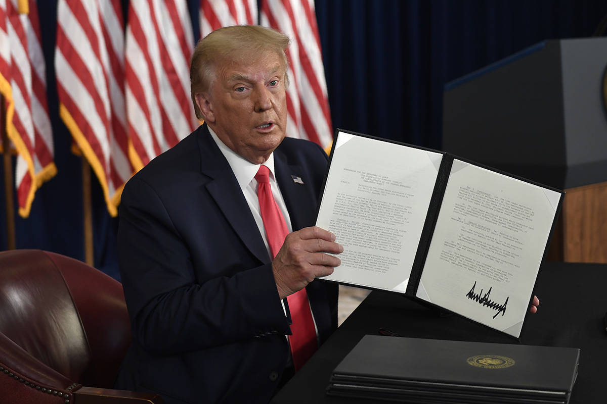 President Donald Trump hold up one of the four executive orders that he signed that addresses t ...