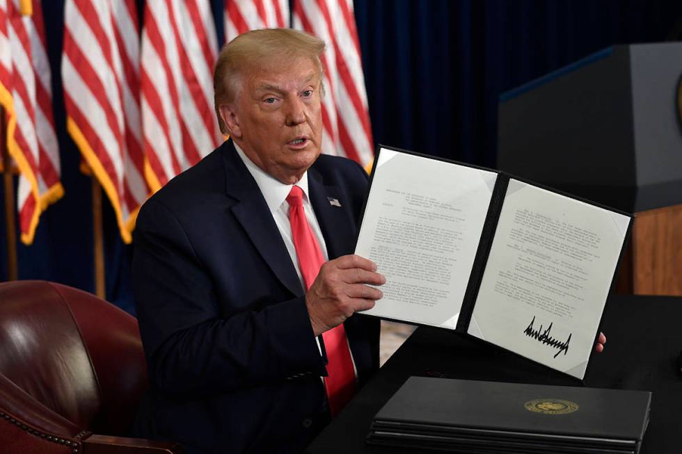 President Donald Trump hold up one of the four executive orders that he signed that addresses t ...