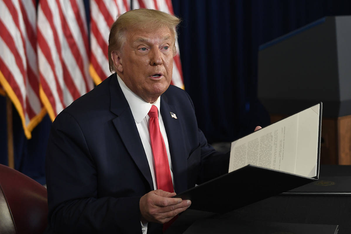 President Donald Trump hold up one of the four executive orders that he signed that addresses t ...