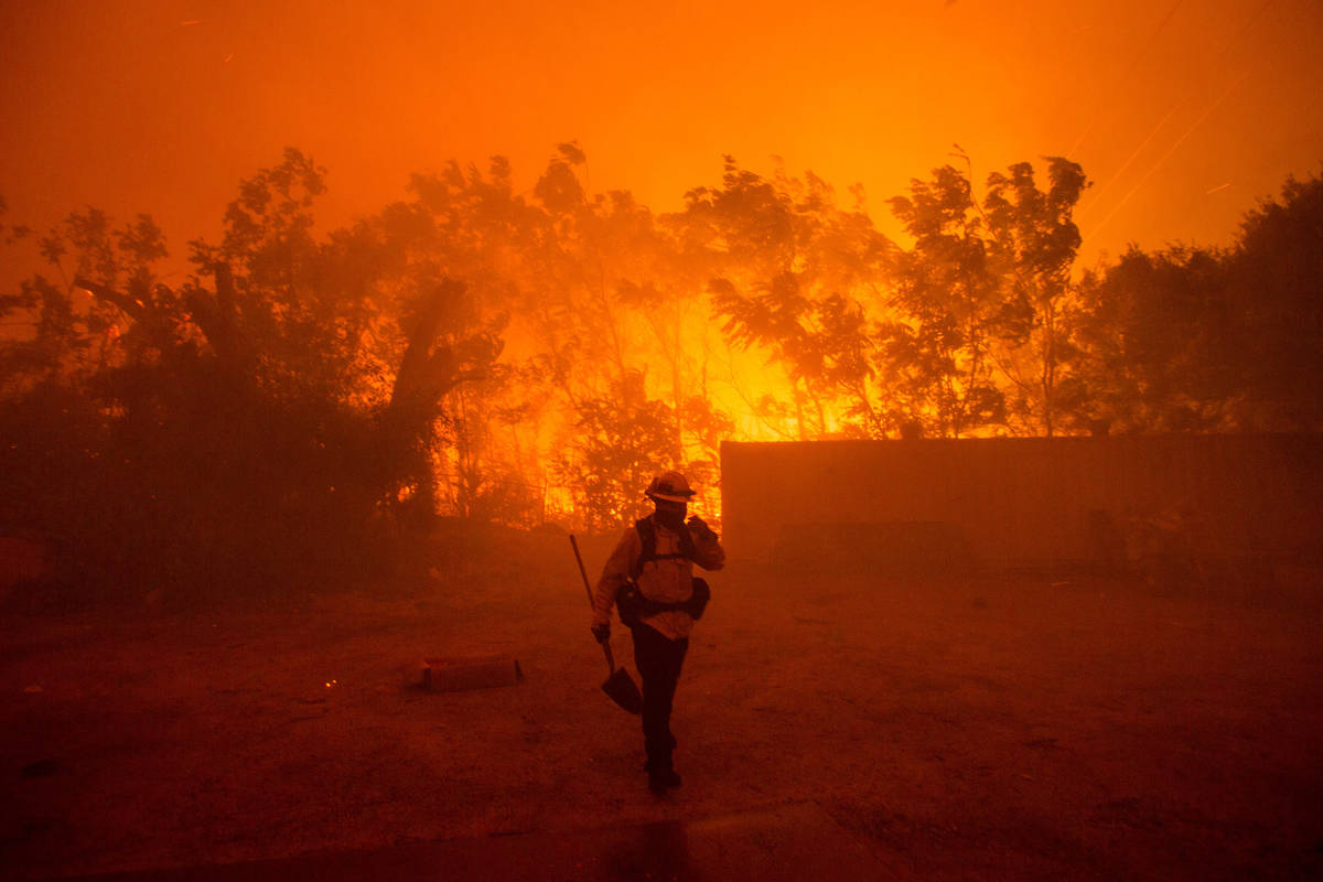 A firefighter walks near an area burning in the Hughes Lake fire in Angeles National Forest on ...