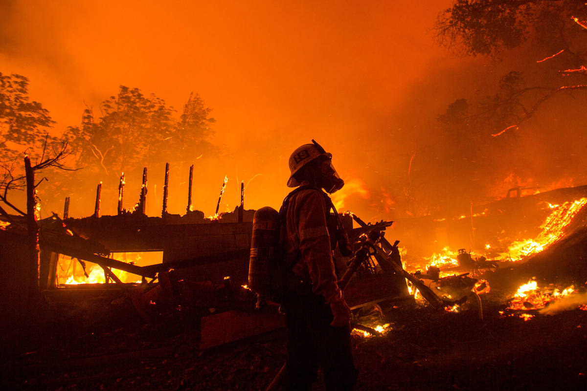 A firefighter watches the Lake Hughes fire consumes a home in Angeles National Forest on Wednes ...