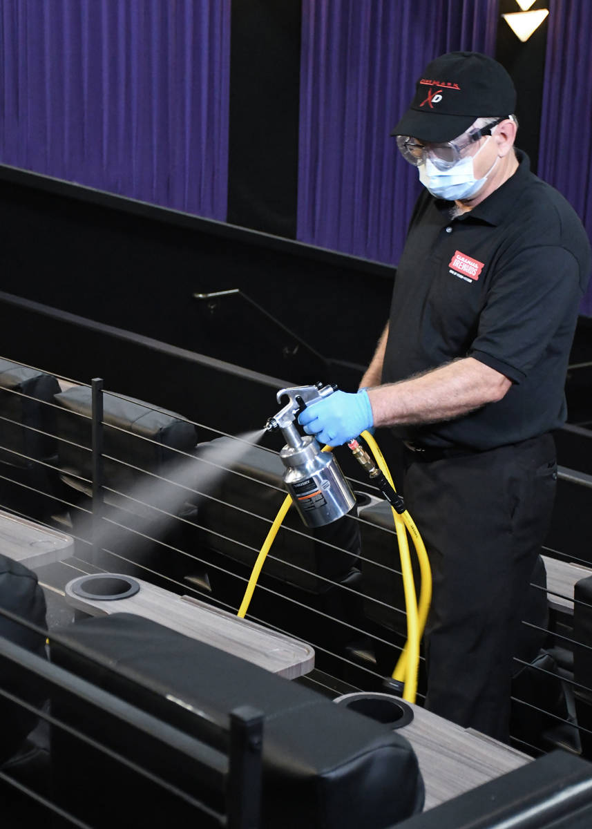 A Cinemark employee cleans inside an auditorium. Five Century-branded movie theaters operated b ...