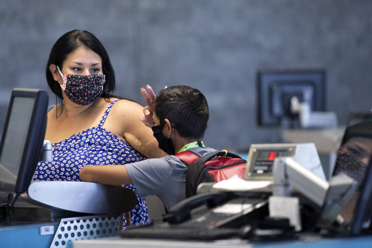 Cynthia Noriega brushes her 11-year-old son Evan York's hair back as they check in for his flig ...
