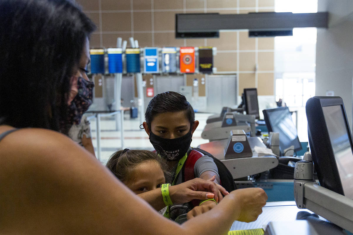 Cynthia Noriega puts a wristband on her son Evan York, 11, before his flight to Washington on S ...