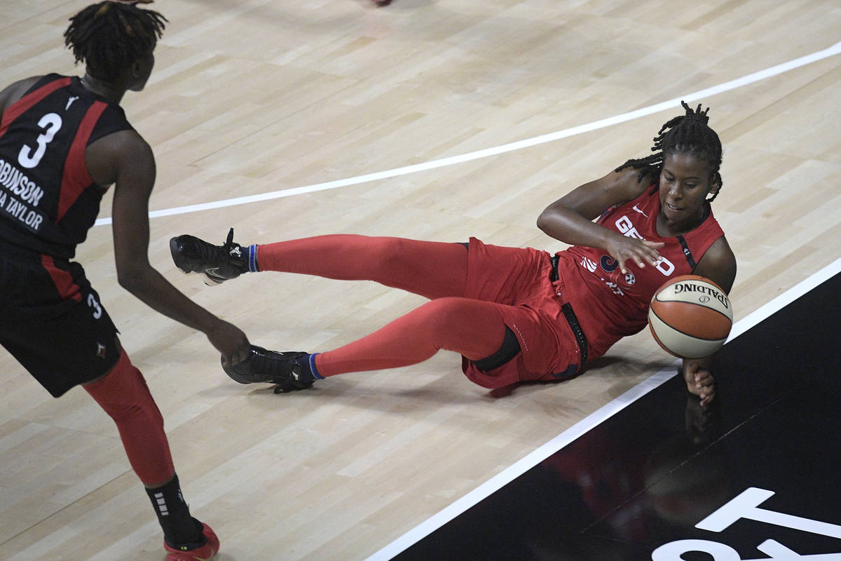 Washington Mystics guard Ariel Atkins, right, dives for a loose ball in front of Las Vegas Aces ...