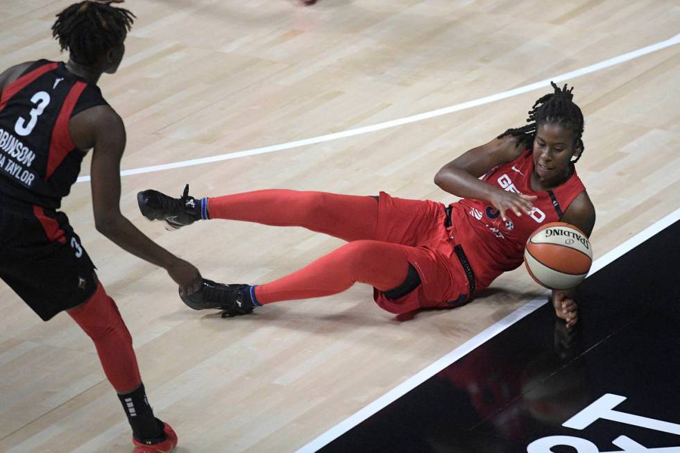Washington Mystics guard Ariel Atkins, right, dives for a loose ball in front of Las Vegas Aces ...