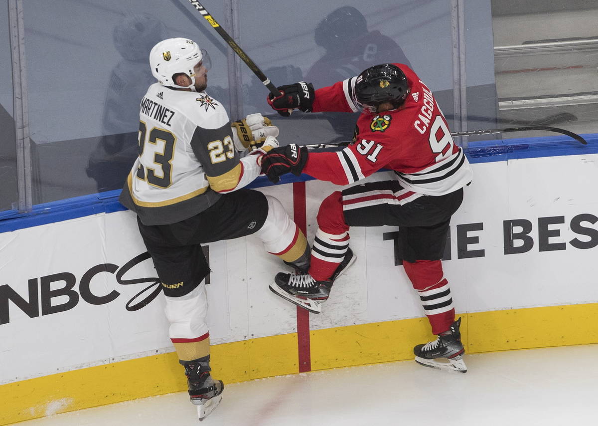 Vegas Golden Knights' Alec Martinez (23) is checked by Chicago Blackhawks' Drake Caggiula (91) ...