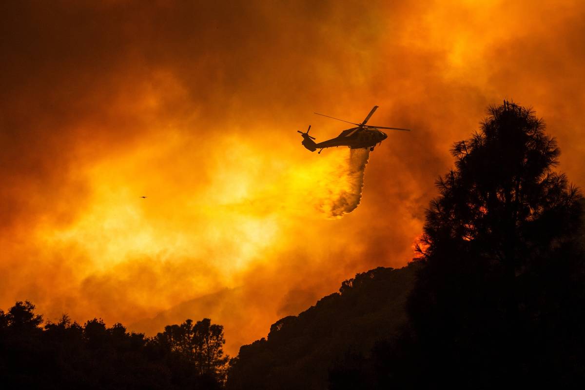 FILE - In this Aug. 12, 2020, file photo, a helicopter drops water on the Lake Hughes Fire in A ...