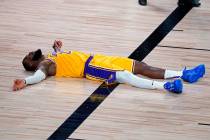 Los Angeles Lakers forward LeBron James (23) lies on the court after committing a foul during t ...