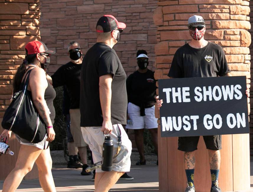 Chaizer Rhodes, trade show worker, holds a sign outside of the Clark County Commission Building ...