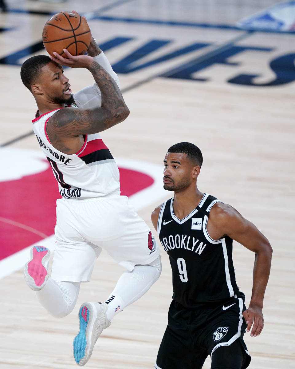 Portland Trail Blazers' Damian Lillard, left, goes up with the ball against Brooklyn Nets' Timo ...