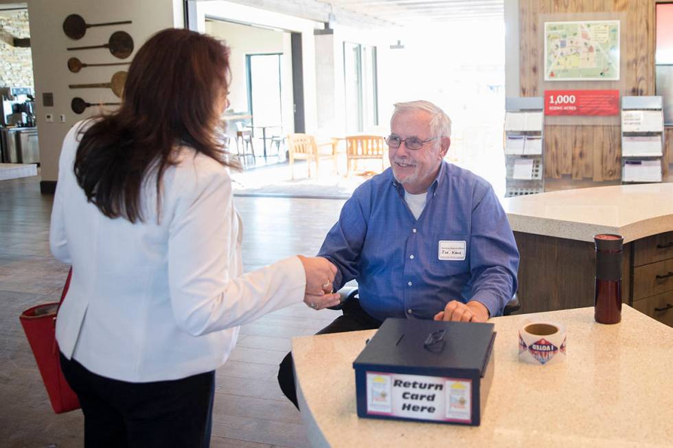 Volunteer Joe Kane, right, hands out "I Voted" stickers at the voting station at 10111 W. Skye ...