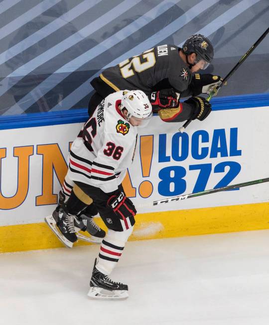 Vegas Golden Knights' Nick Holden (22) is checked by Chicago Blackhawks' Matthew Highmore (36) ...