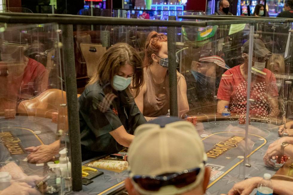 Individuals play eight-handed poker games using plexiglass dividers between the players in the ...