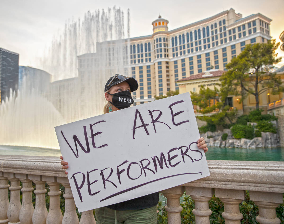 Michelle Prentiss holds a sign on the Strip in front of the Bellagio fountains during an event ...