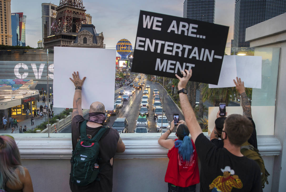 Entertainment workers cheer as a motorcade of their peers drive south on the Strip during an ev ...