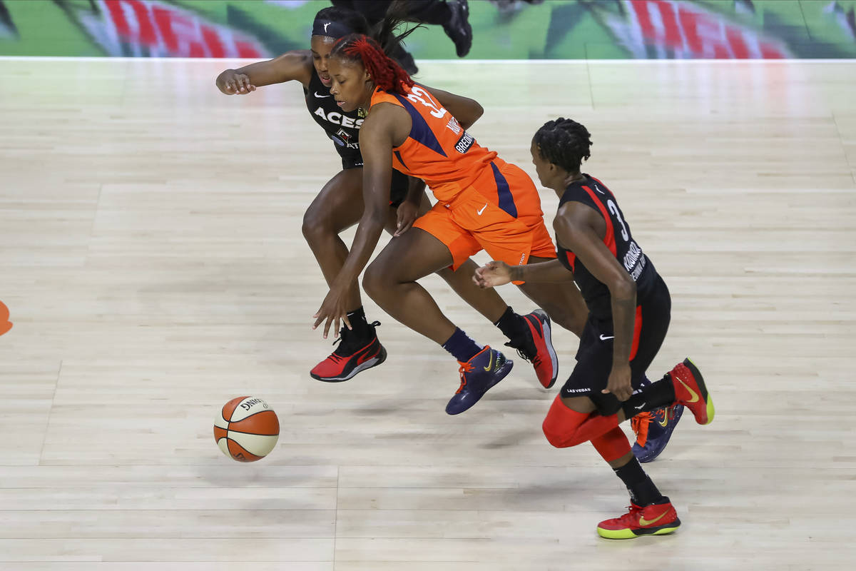Connecticut Sun's Bria Holmes (32) drives between Las Vegas Aces' Jackie Young, left, and Danie ...
