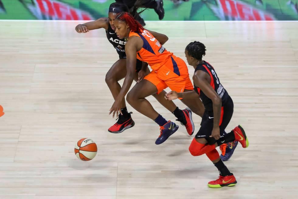 Connecticut Sun's Bria Holmes (32) drives between Las Vegas Aces' Jackie Young, left, and Danie ...