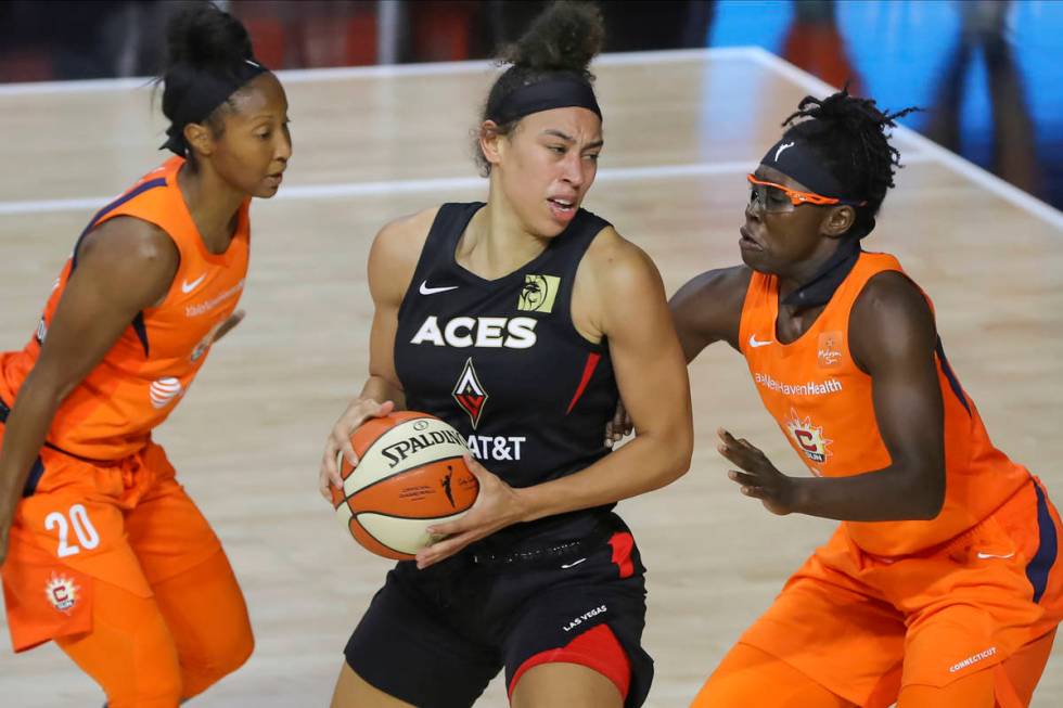 Las Vegas Aces' Dearica Hamby, center, drives between Connecticut Sun's Briann January (20) and ...