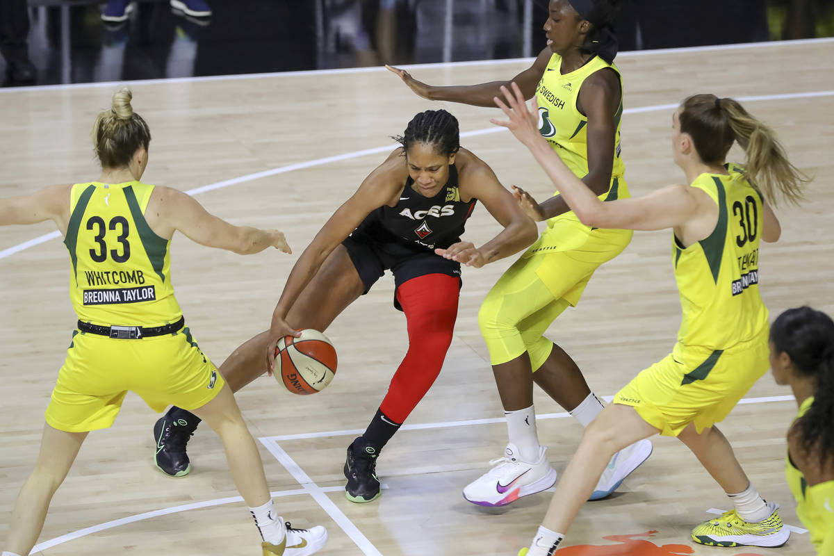 Las Vegas Aces' A'ja Wilson, center, drives against the Seattle Storm of, from left, Sami Whitc ...