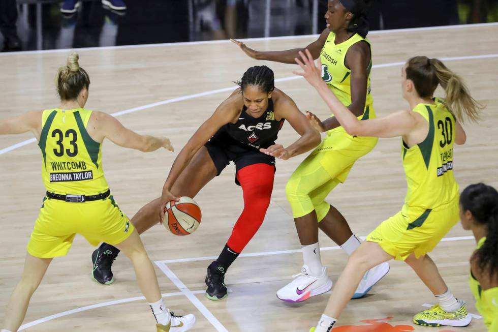 Las Vegas Aces' A'ja Wilson, center, drives against the Seattle Storm of, from left, Sami Whitc ...