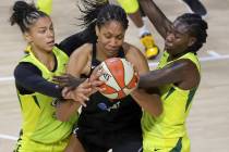 Las Vegas Aces' A'ja Wilson, center, is defended by Seattle Storm's Alysha Clark, left, and Nat ...