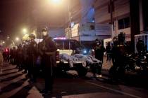 Police officers stand guard near two bodies outside of a disco in Lima, Peru, Sunday, Aug. 23, ...