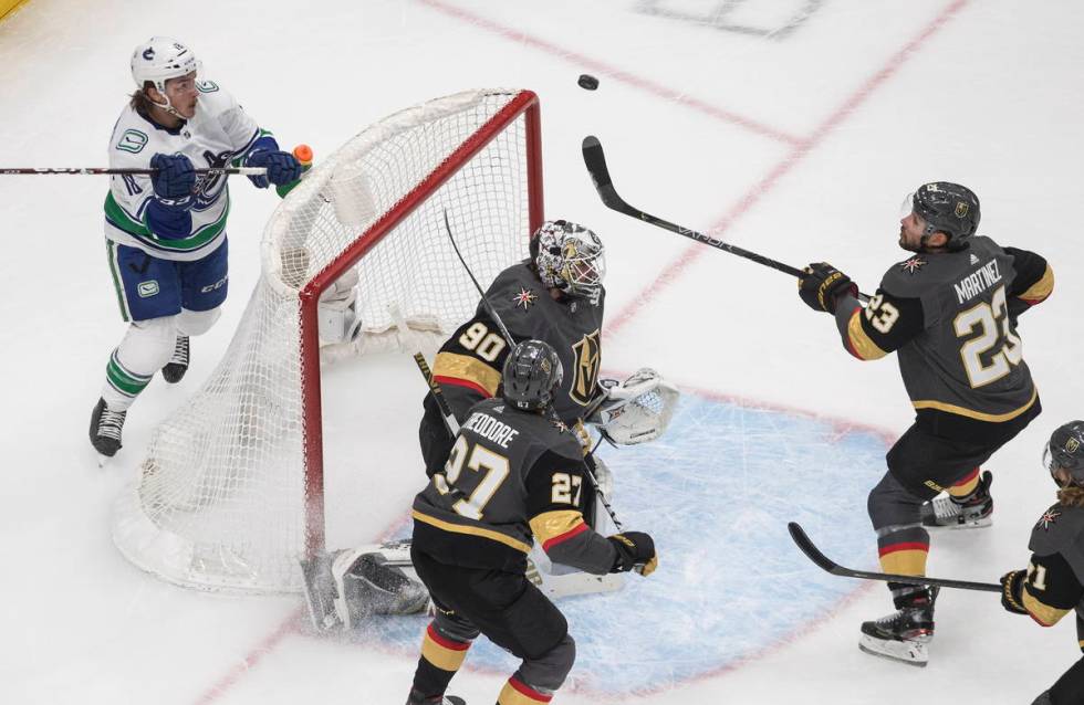 Vegas Golden Knights' Shea Theodore (27) watches as teammate Robin Lehner (90) makes the save a ...