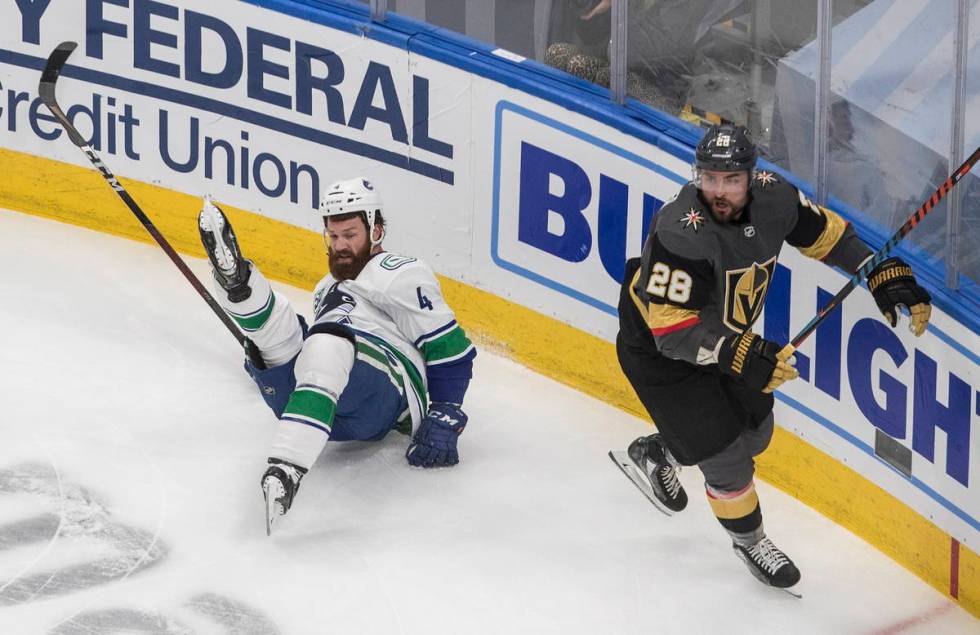 Vegas Golden Knights' William Carrier (28) checks Vancouver Canucks' Jordie Benn (4) during the ...