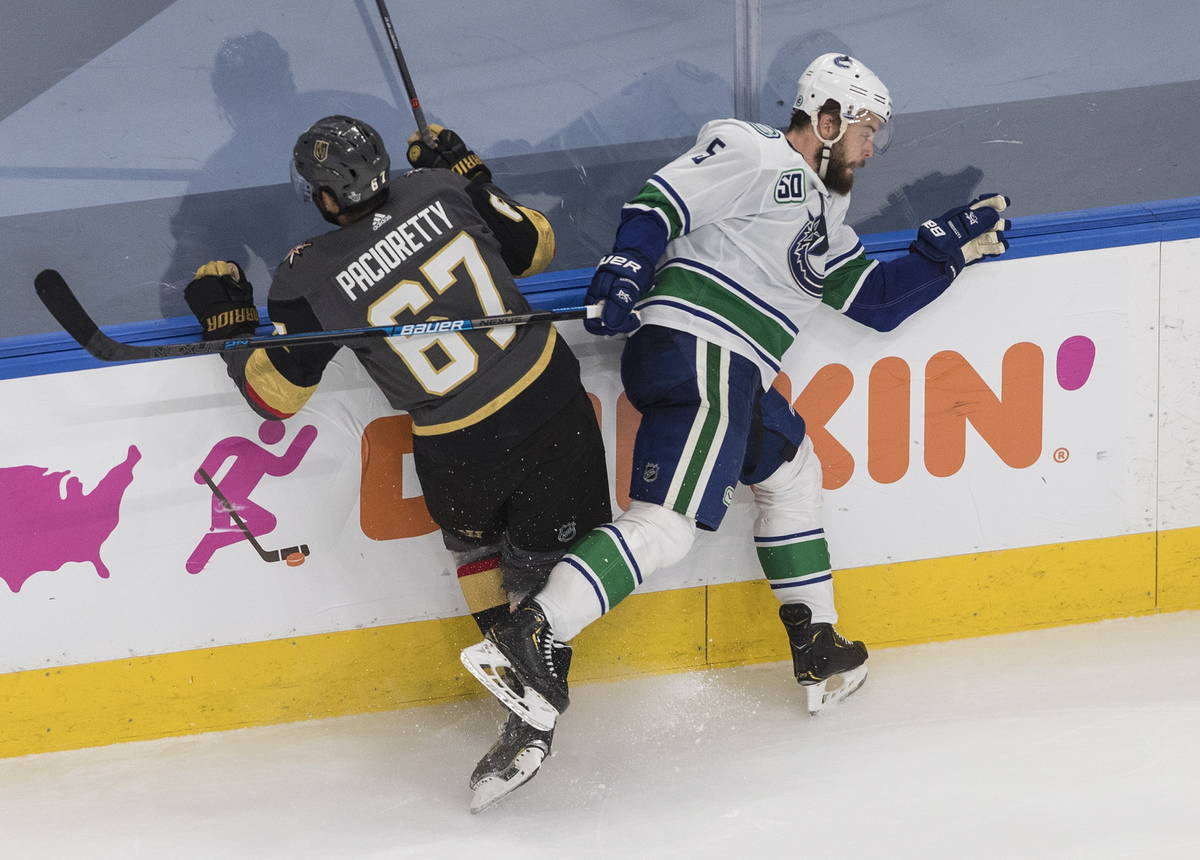 Vegas Golden Knights' Max Pacioretty (67) is checked by Vancouver Canucks' Oscar Fantenberg (5) ...