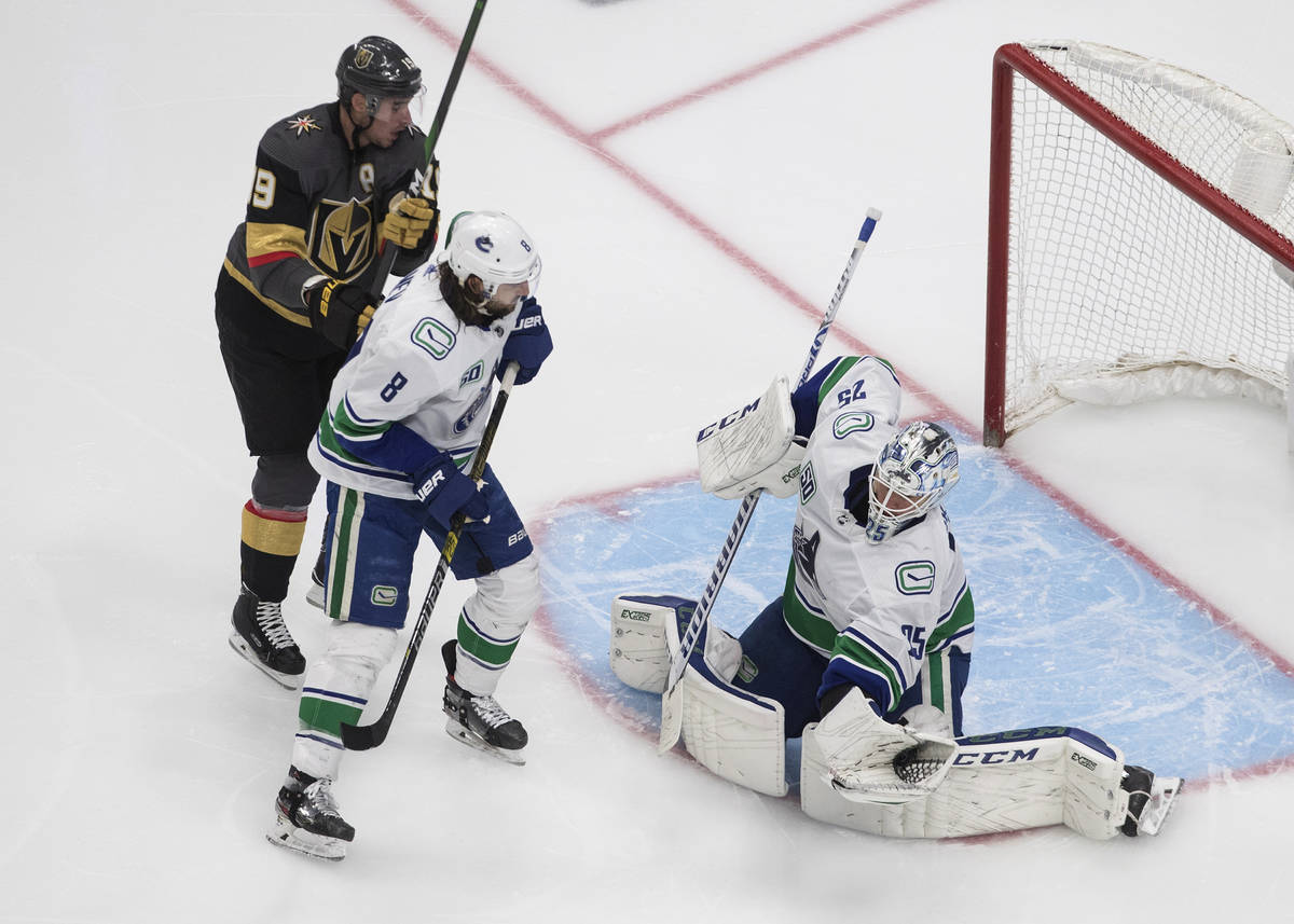 Vegas Golden Knights' Reilly Smith (19) and Vancouver Canucks' Christopher Tanev (8) watch as C ...