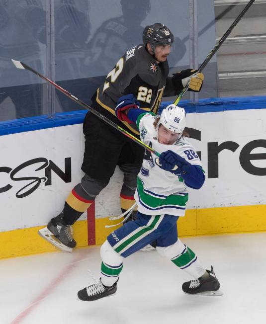 Vegas Golden Knights' Nick Holden (22) is checked by Vancouver Canucks' Adam Gaudette (88) duri ...