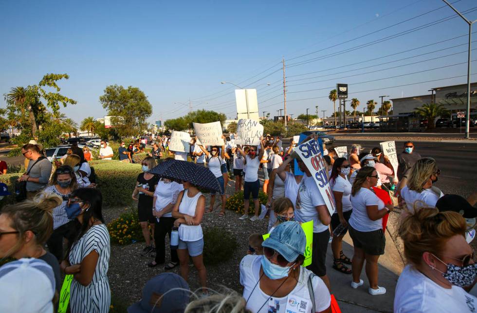 People listen to speakers during a demonstration in support of reopening public schools outside ...