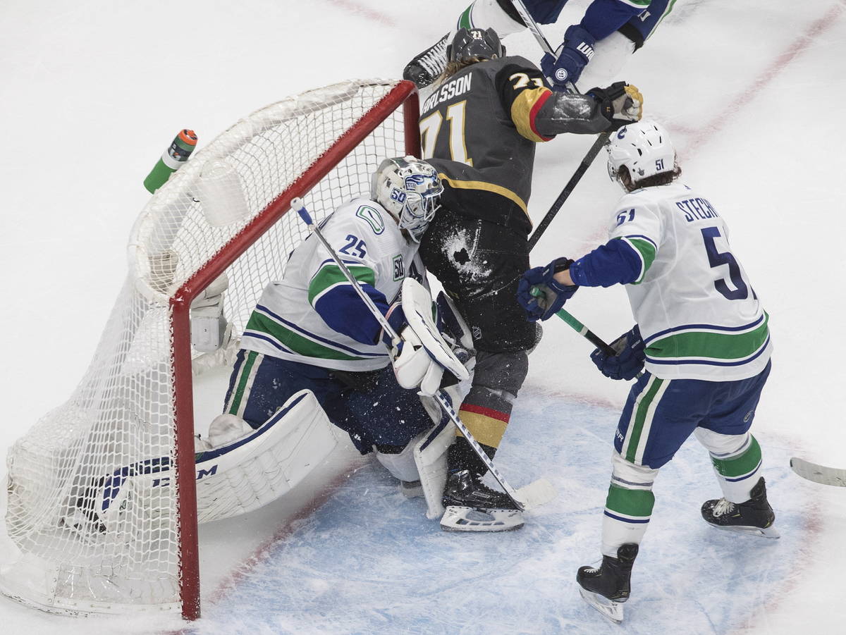 Vegas Golden Knights' William Karlsson (71) crashes against Vancouver Canucks goalie Jacob Mark ...