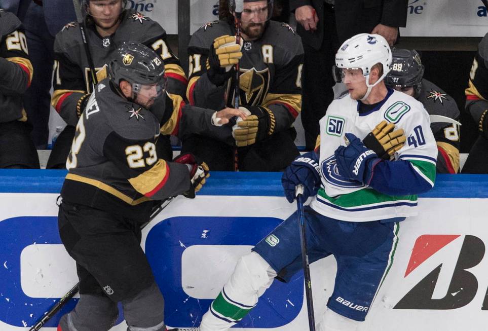 Vegas Golden Knights' Alec Martinez (23) gets his glove taken by Vancouver Canucks' Elias Pette ...