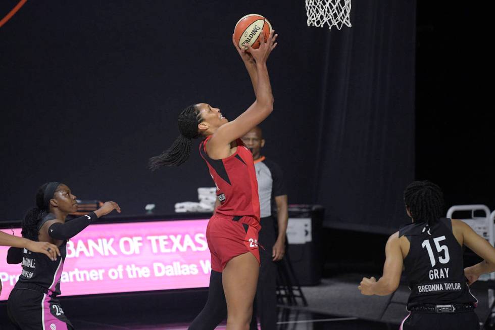 Las Vegas Aces center A'ja Wilson (22) goes up for a shot between Dallas Wings guards Arike Ogu ...